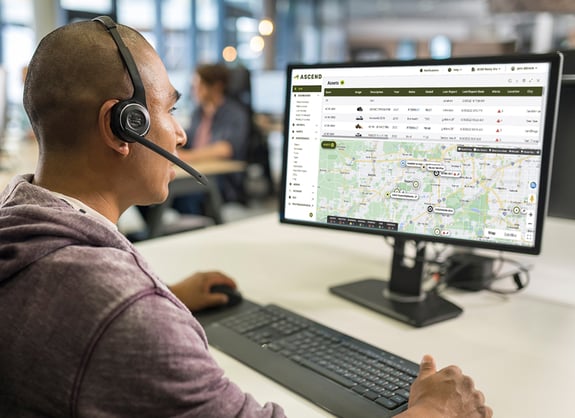 person in headset at desk using ascend telematics asset tracking software on screen