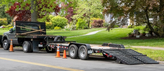 Landscaping truck with empty flatbed trailer with ramp parked on residential neighborhood street